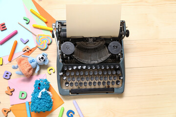 Composition with vintage typewriter, knitted toys and beige paper on light wooden background