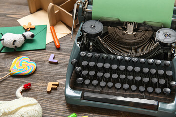 Beautiful composition with vintage typewriter, knitted toys and green paper on dark wooden...