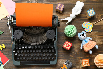 Vintage typewriter with orange paper and knitted toys on dark wooden background