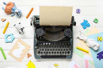 Composition with vintage typewriter, knitted toys and beige paper on white wooden background