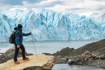 Homem com mochila caminhando e explora geleira azul na Patagônia.
