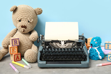 Beautiful composition with vintage typewriter and knitted toys on table near blue wall