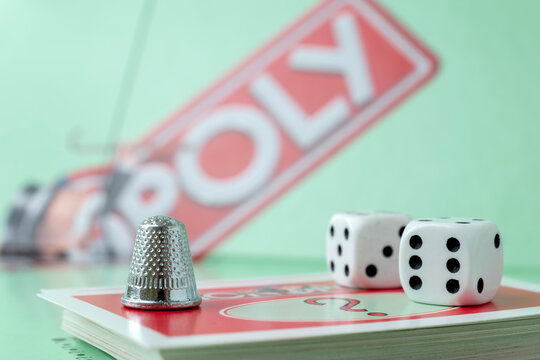 Kaunas, Lithuania - July 2021: close up of monopoly thimble token, monopoly board and dices on the monopoly chance cards.