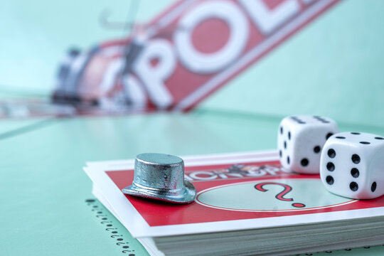 Kaunas, Lithuania - July 2021: close up of monopoly hat token, monopoly board and dices on the monopoly chance cards.