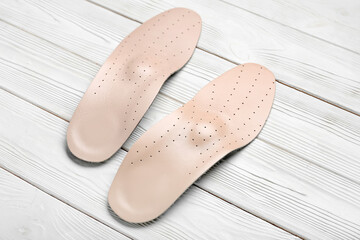 Leather orthopedic insoles on white wooden background