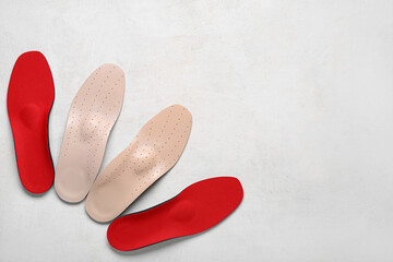 Two pairs of red and beige orthopedic insoles on white background