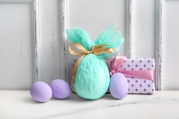Painted and chocolate Easter eggs wrapped in paper with gift box on white grunge background