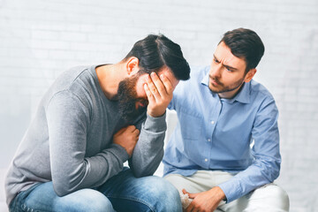 Group members comforting crying addicted man at rehab session
