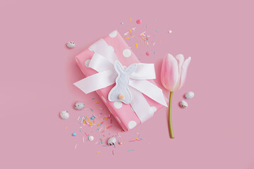 Gift box with tulip flower and Easter toy bunny on pink background