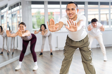 Portrait of active young man enjoying modern energetic dancing in group at street dance studio