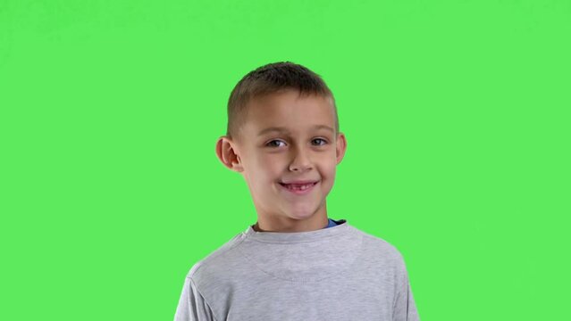 Portrait of a smiling boy with a green screen in the background

