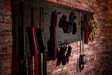 A set of BDSM equipment hanging on the wall.  - obrazy, fototapety, plakaty