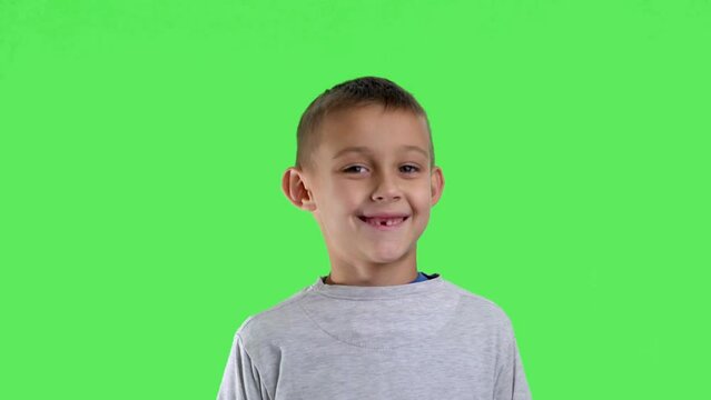 Portrait of a smiling boy with a green screen in the background

