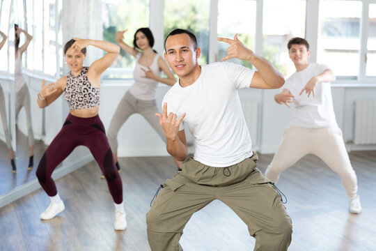 During dance workshop, guy enjoys active dancing, learns new movements, moves synchronously with participants of lesson. Concept of beautiful body through sports, dancing, and active lifestyle