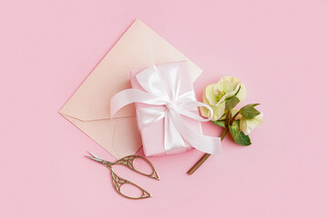 Gift box with beautiful flowers and envelope on pink background