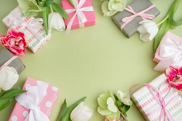Frame made of gift boxes and beautiful flowers on green background