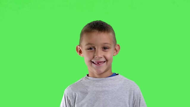 Portrait of a smiling boy with a green screen in the background

