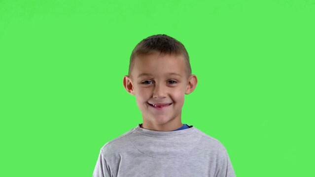 Portrait of a smiling boy with a green screen in the background

