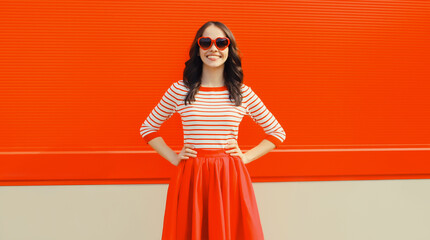 Beautiful happy smiling young brunette woman posing in red heart shaped sunglasses, skirt in city