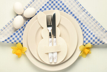 Festive table setting with Easter eggs, flowers and napkin on white background