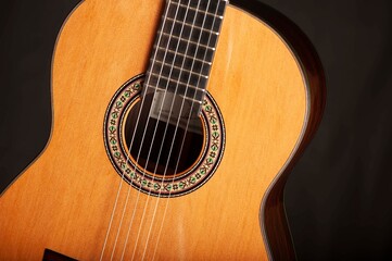 Naklejka premium Classical Spanish flamenco guitar close up, dramatically lit isolated on black background with copy space.