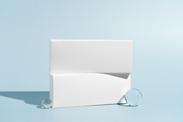 Two white mockup boxes of pills, antibiotics or oral contraceptives on a blue isolated background....