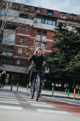 Urban scene with a focused male bicyclist using a smart phone while crossing a zebra crossing in the city during daytime.