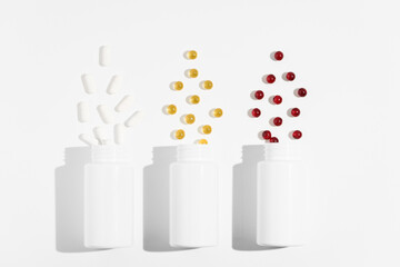 Three mockup blank jars with white, yellow and red pills capsules on white isolated background. Concept of health, medicines, pharmacy and dietary supplements. Image for your design