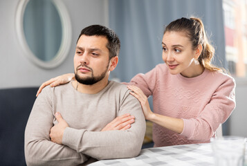 Tender loving young woman comforting distressed offended husband after spat while sitting together...