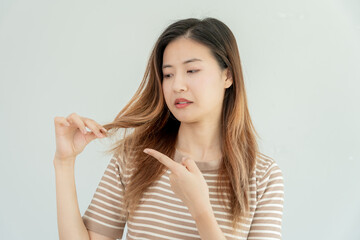 Asian woman very sad and upset looking at damaged hair, hair loss, hair thinning problem, vitamin...