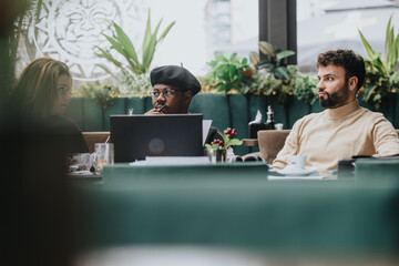 A focused multiethnic group of business associates in casual attire is collaboratively working with laptops at a stylish restaurant setting.