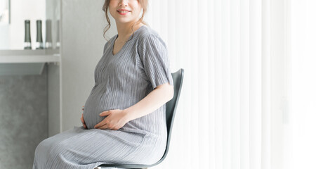 家のリビングで椅子に座る妊婦・マタニティフォト
