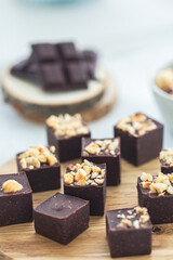 Irresistible Homemade Chocolate Fudge Cubes Decorated with Nuts on Wooden Board, Organic healthy food