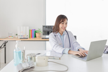 Asian female doctor typing report with laptop, she feeling happy and relax in hospital, Medical online technology