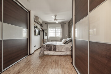 Bedroom with two large built-in wardrobes with dark wooden sliding doors