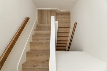 stairs with wooden steps and beech wood railings in the interior of a single-family residential home in a minimalist style