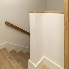 Stairs with wooden steps and oak handrails in the interior of a detached house in minimalist style