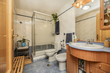 A contemporary bathroom with white tiles and blue floors, white toilets, and a square shower cubicle with screens