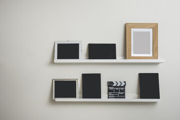 white wooden shelves with several black frames a movie clapperboard leaning on it