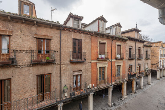Beautiful views of the main street of Alcal&aacute; de Henares with very old buildings and people walking through the arcades