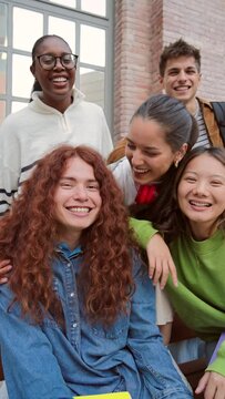 Vertical portrait of a group of friends having fun and smiling together. High school students looking at camera with happy expression. Young friendly real people staring front posing for a photo