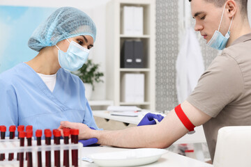 Laboratory testing. Doctor taking blood sample from patient at white table in hospital
