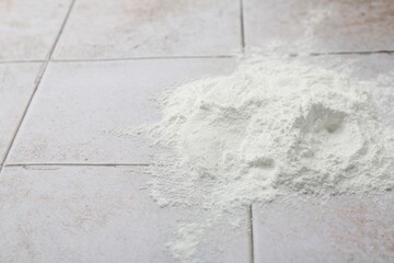 Pile of baking powder on light tiled table, closeup. Space for text