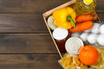 Crate with donation food on wooden table, top view. Space for text