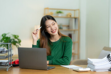 Fototapeta na wymiar Ambitious Asian girl working from home Looking at laptop screen and smiling, checking mail or doing research while working remotely, online startup business, telemarketing