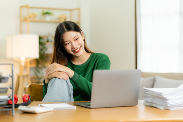 Ambitious Asian girl working from home Looking at laptop screen and smiling, checking mail or doing research while working remotely, online startup business, telemarketing