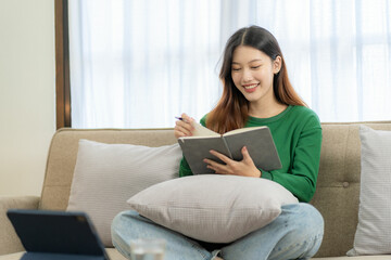 Obraz premium Ambitious Asian girl working from home Looking at laptop screen and smiling, checking mail or doing research while working remotely, online startup business, telemarketing
