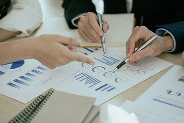 A team of analysts works on a financial data analysis dashboard on paper to use as market...