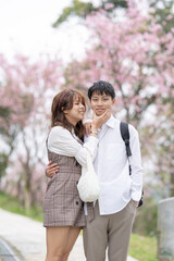 A young Taiwanese male and female couple in their 20s are taking a walk while talking happily in the mountains where the cherry blossoms of the Maokong are blooming, a tourist destination in Taiwan. 2