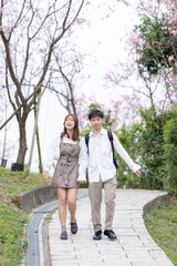 Fototapeta na wymiar A young Taiwanese male and female couple in their 20s are taking a walk while talking happily in the mountains where the cherry blossoms of the Maokong are blooming, a tourist destination in Taiwan. 2